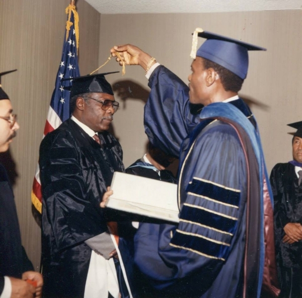 Faculty member turning a graduate's tassel while presenting a diploma case