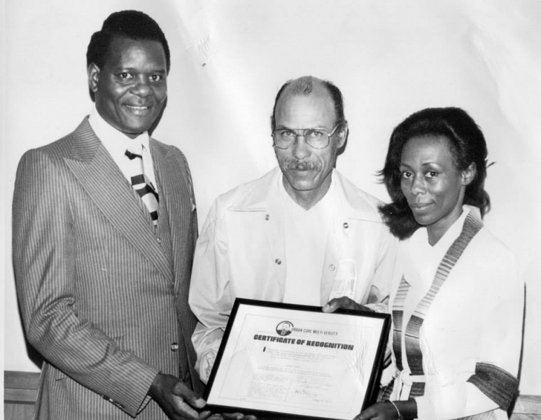 Three people holding a framed Certificate of Recognition