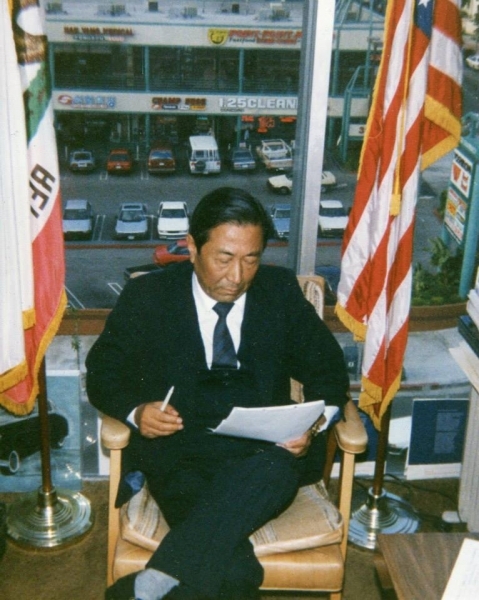 University officer reviewing documents in an office flanked by flags