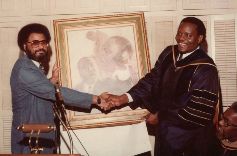University officer shaking hands with a donor beside a presented commemorative painting