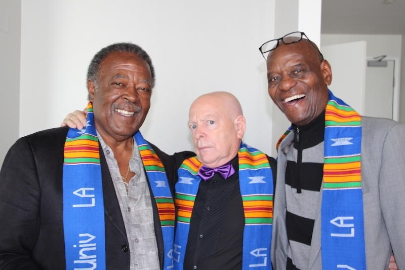 Three university colleagues laughing together in kente stoles