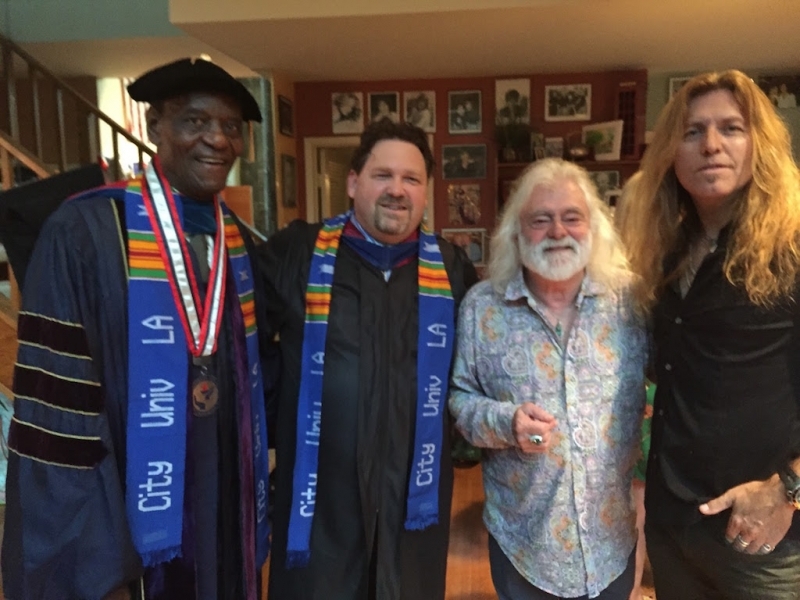 Faculty in regalia standing with two guests after a ceremony