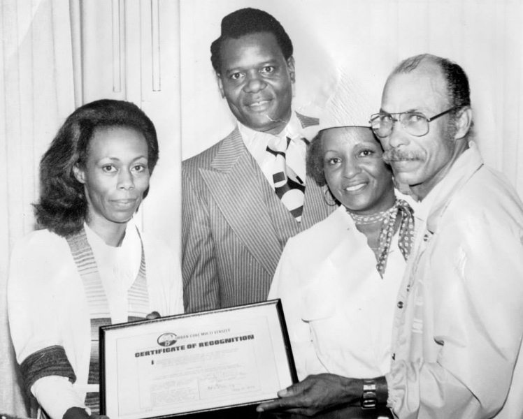 Four people holding a framed Certificate of Recognition