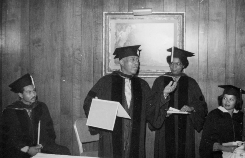 Faculty in caps and gowns addressing graduates during a conferral of degrees