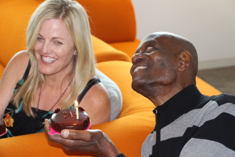 Two guests laughing together while holding a candlelit cake