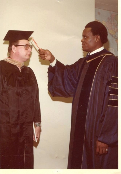 University officer adjusting the tassel of a graduate in regalia