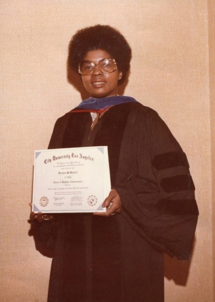 Graduate in regalia holding a City University Los Angeles Bachelor of Business Administration diploma