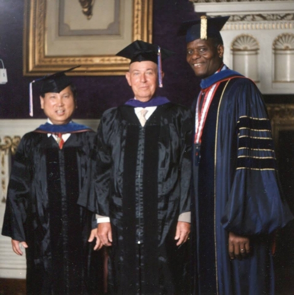 Three faculty members in doctoral regalia posing together before a ceremony