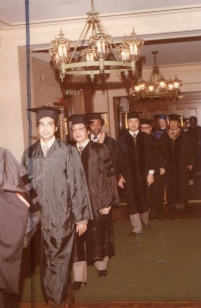 Graduates walking in processional through a chandeliered hall