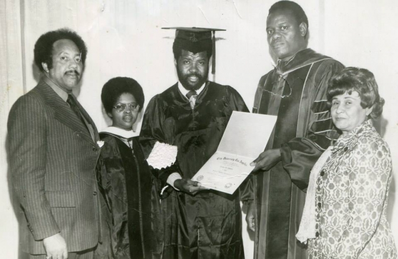 Graduate holding a City University Los Angeles diploma with faculty and family