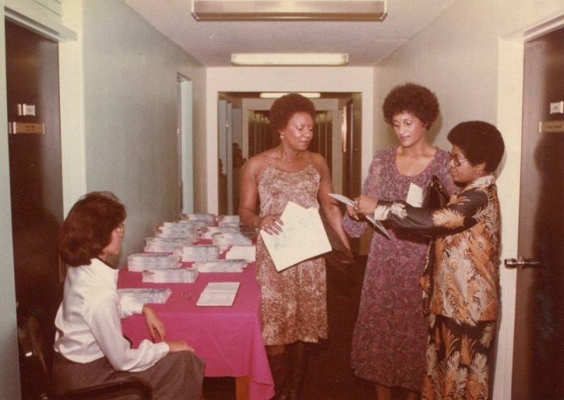 Students collecting documents at a registration table in a corridor