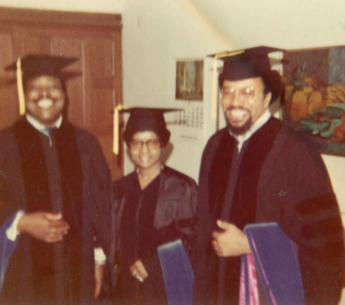 Three graduates in doctoral regalia smiling before the ceremony