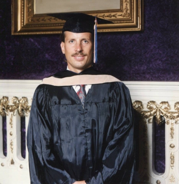 Formal portrait of a graduate in cap, gown and academic hood