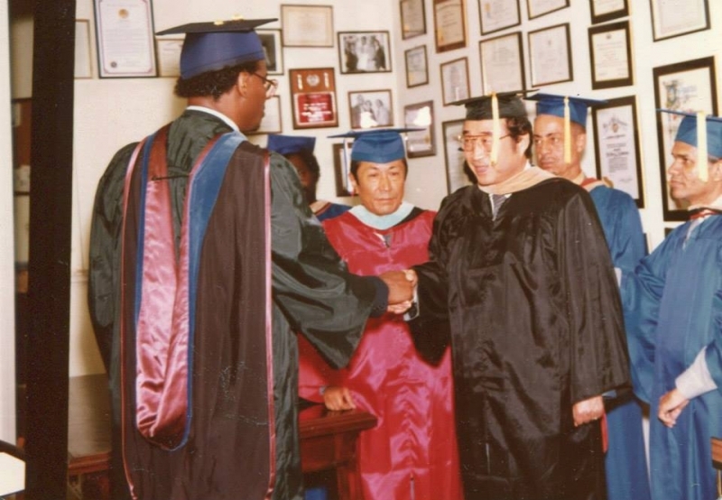 Graduates congratulating one another in a room lined with framed awards