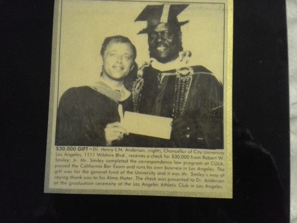 Framed newspaper clipping showing Chancellor Henry L. N. Anderson receiving a $30,000 gift cheque from alumnus Robert W. Smiley, Jr.