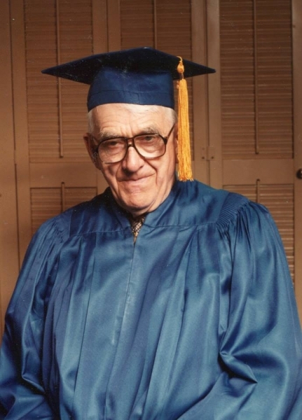 Graduate in blue cap and gown posing for a commencement portrait