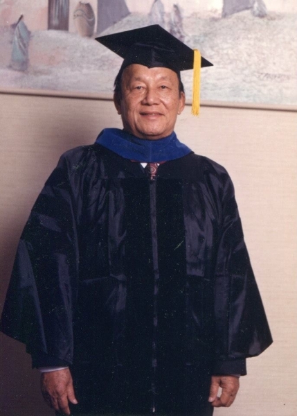 Graduate in doctoral cap and gown posing for a portrait