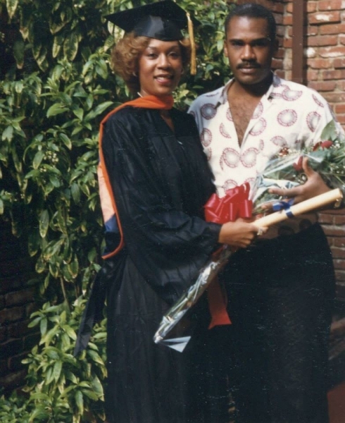 Graduate holding flowers and a diploma scroll with a family member