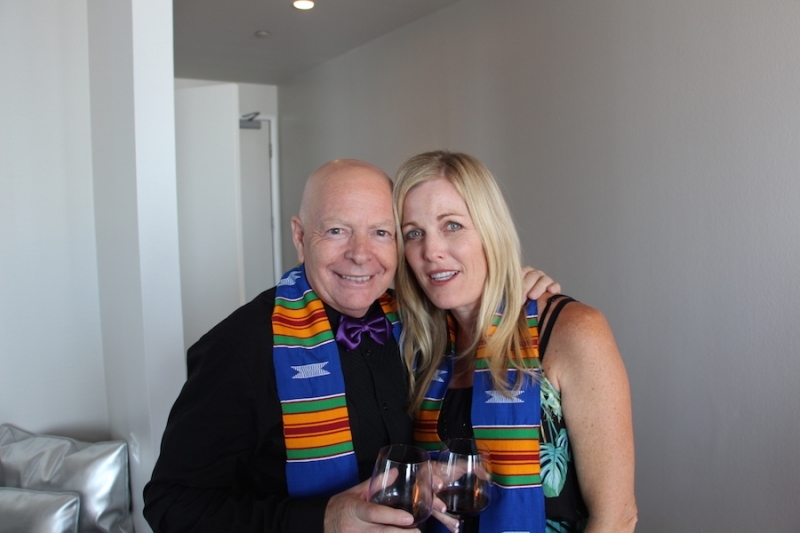Two guests in university stoles raising glasses of wine at a reception