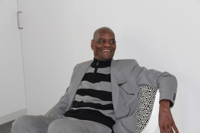 Portrait of a university leader seated in a white lounge chair
