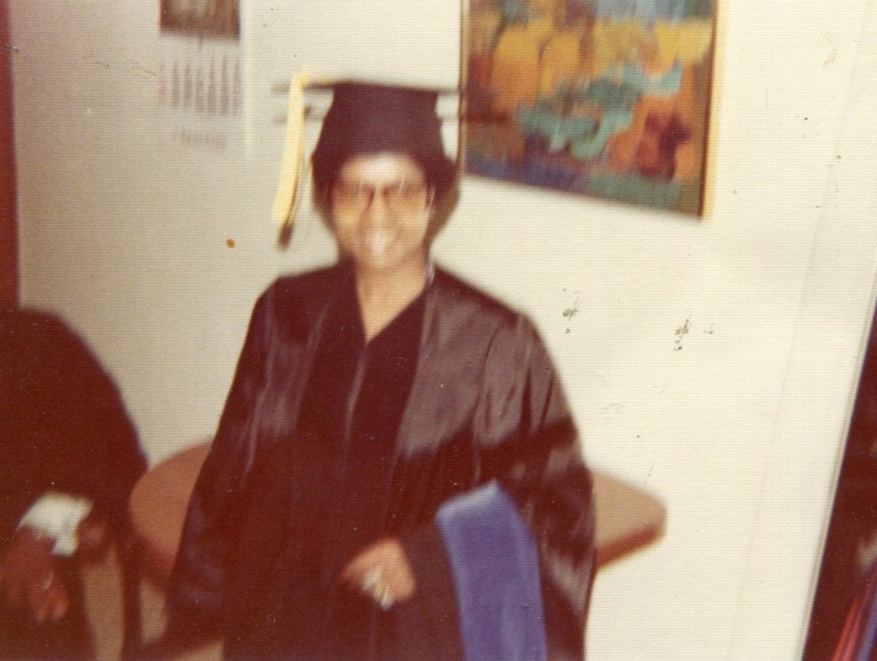 Graduate in cap and gown smiling in a campus office