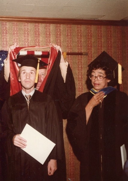 Faculty placing an academic hood over a graduate during the ceremony
