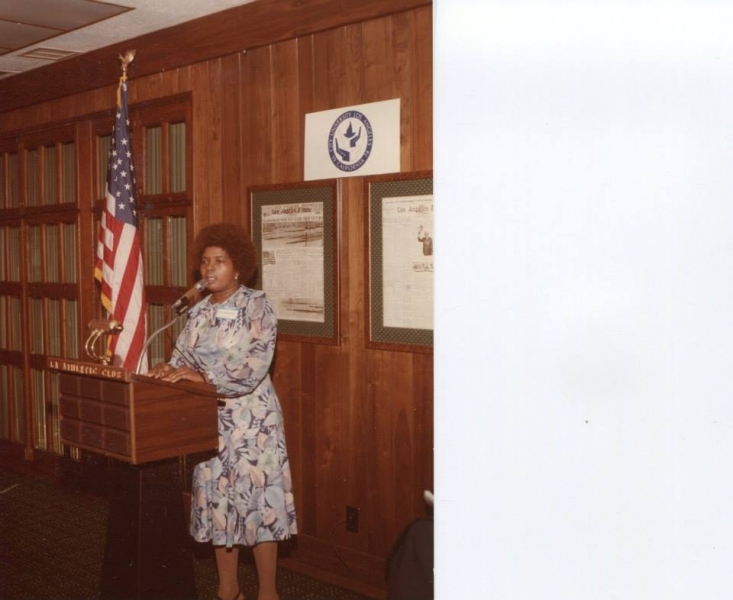 Speaker addressing guests from a podium beneath the university seal