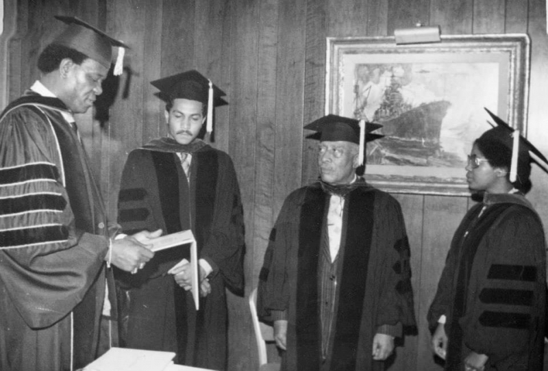 Faculty members in regalia reviewing documents before a ceremony
