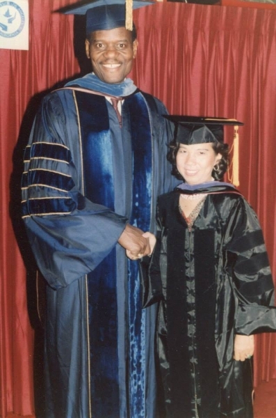 University president in blue regalia standing with a graduate