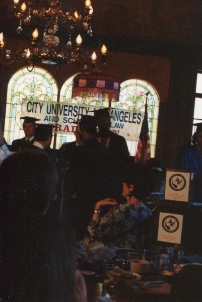 Graduation banquet beneath stained glass windows with a City University Los Angeles banner